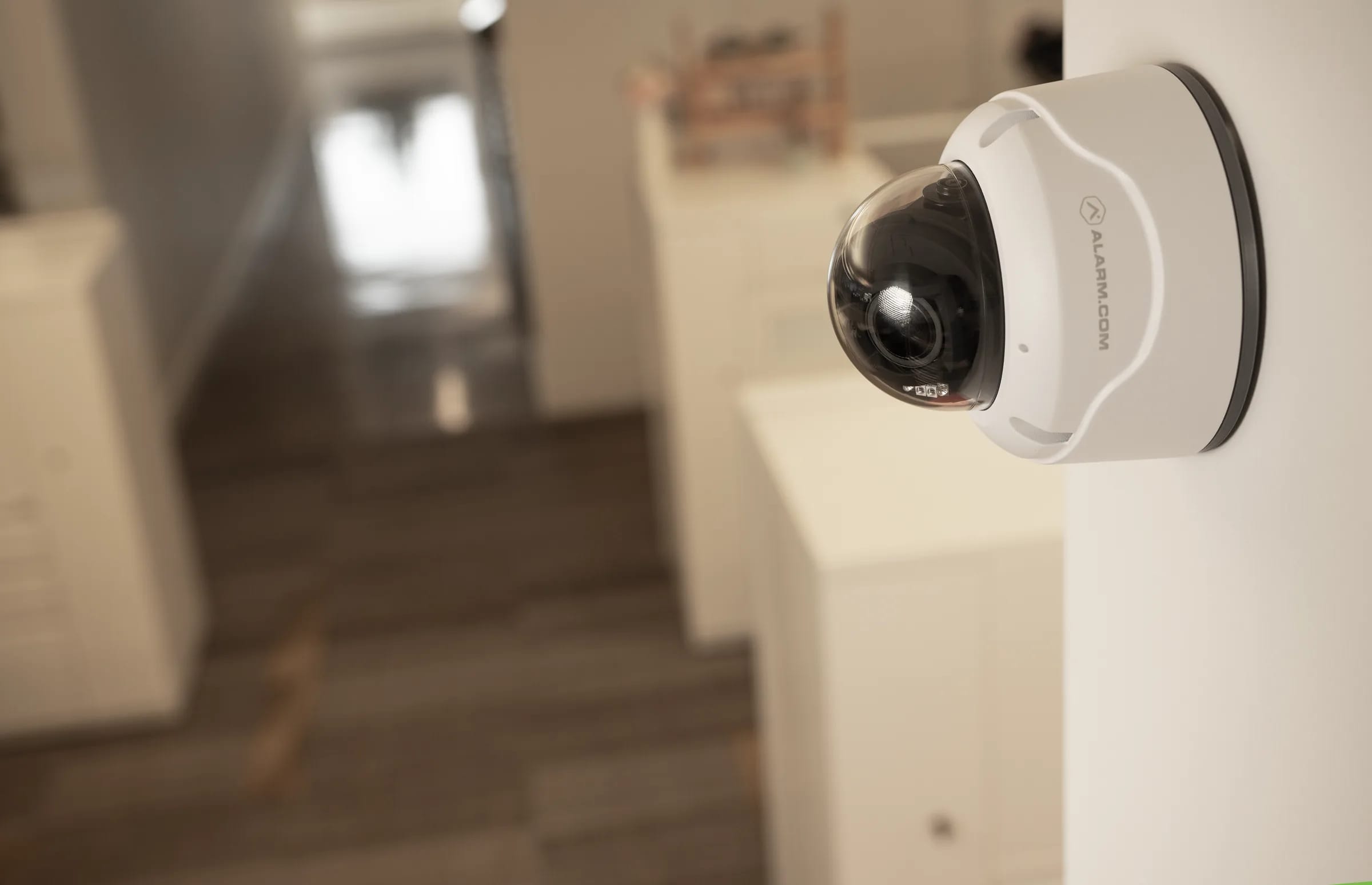 Alarm.com wall-mount dome security camera monitoring a bright residential interior