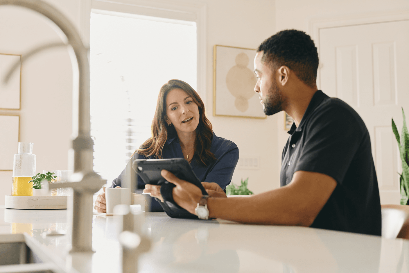 Two people reviewing a security system on a tablet at a kitchen counter