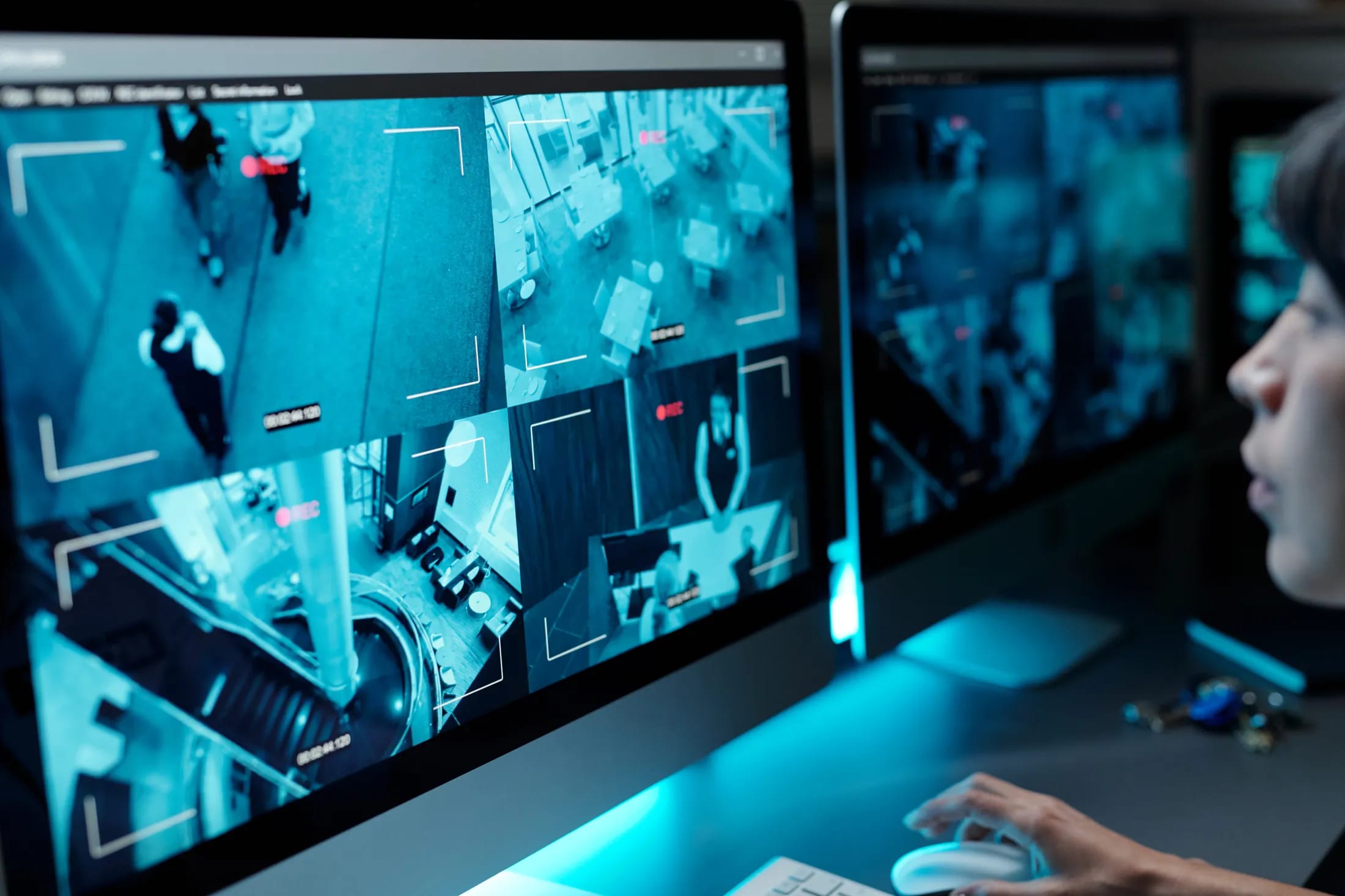A security operator monitoring a wall of live CCTV camera feeds in a surveillance control room, turning security data into operational insight