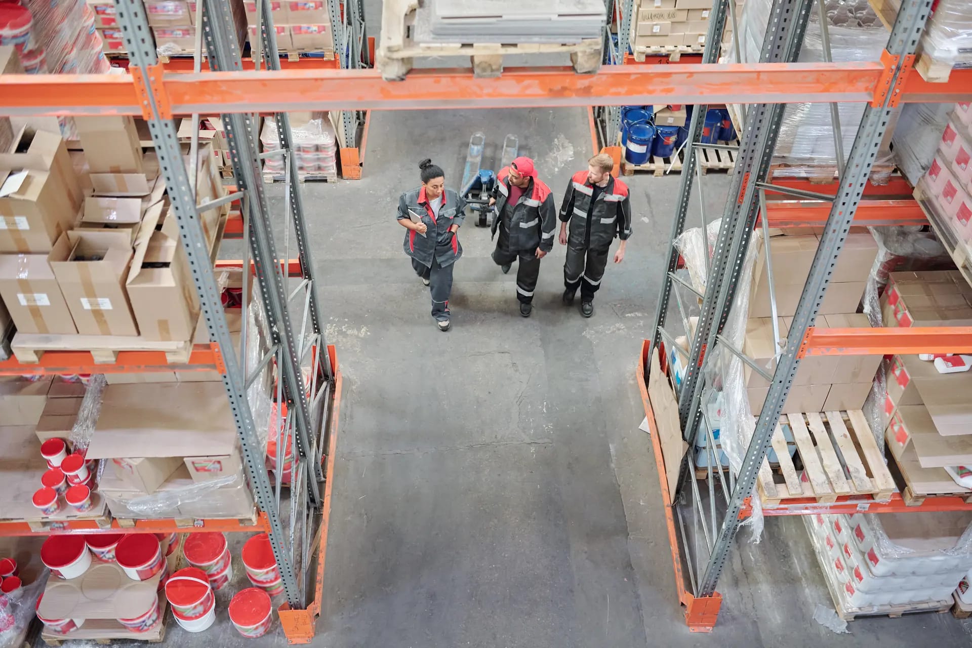 Two warehouse workers walking a stocked aisle in a large distribution facility