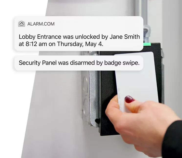 A hand swiping a white access card on a wall-mounted card reader, with Alarm.com notifications confirming the lobby entrance was unlocked and the security panel disarmed by badge swipe