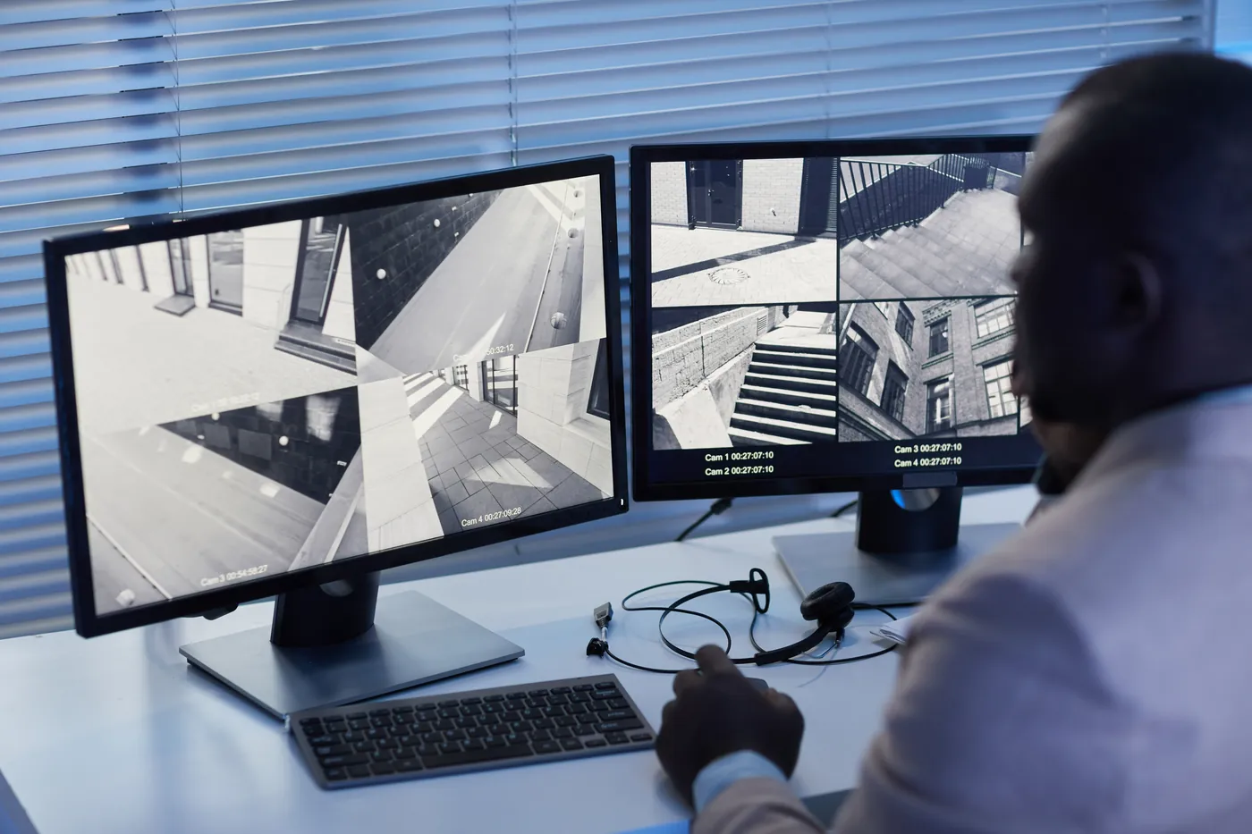 Security operator reviewing live CCTV surveillance footage across dual monitors in a commercial control room