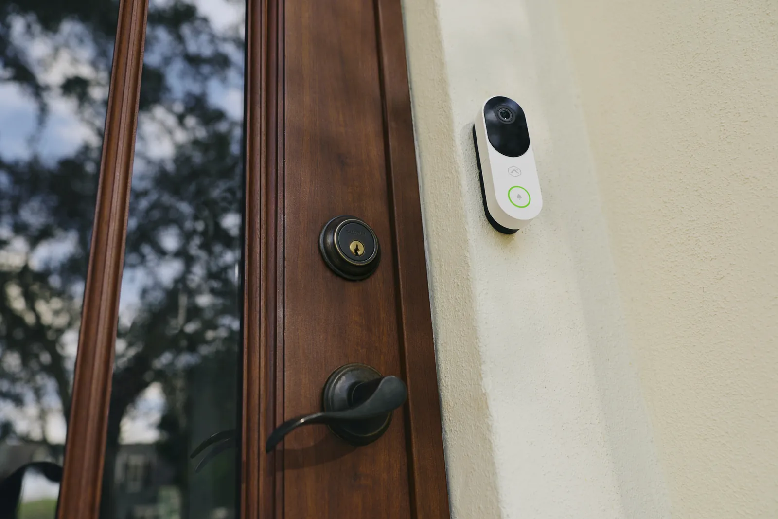 A smart video doorbell camera with a glowing status ring mounted beside a home's front door