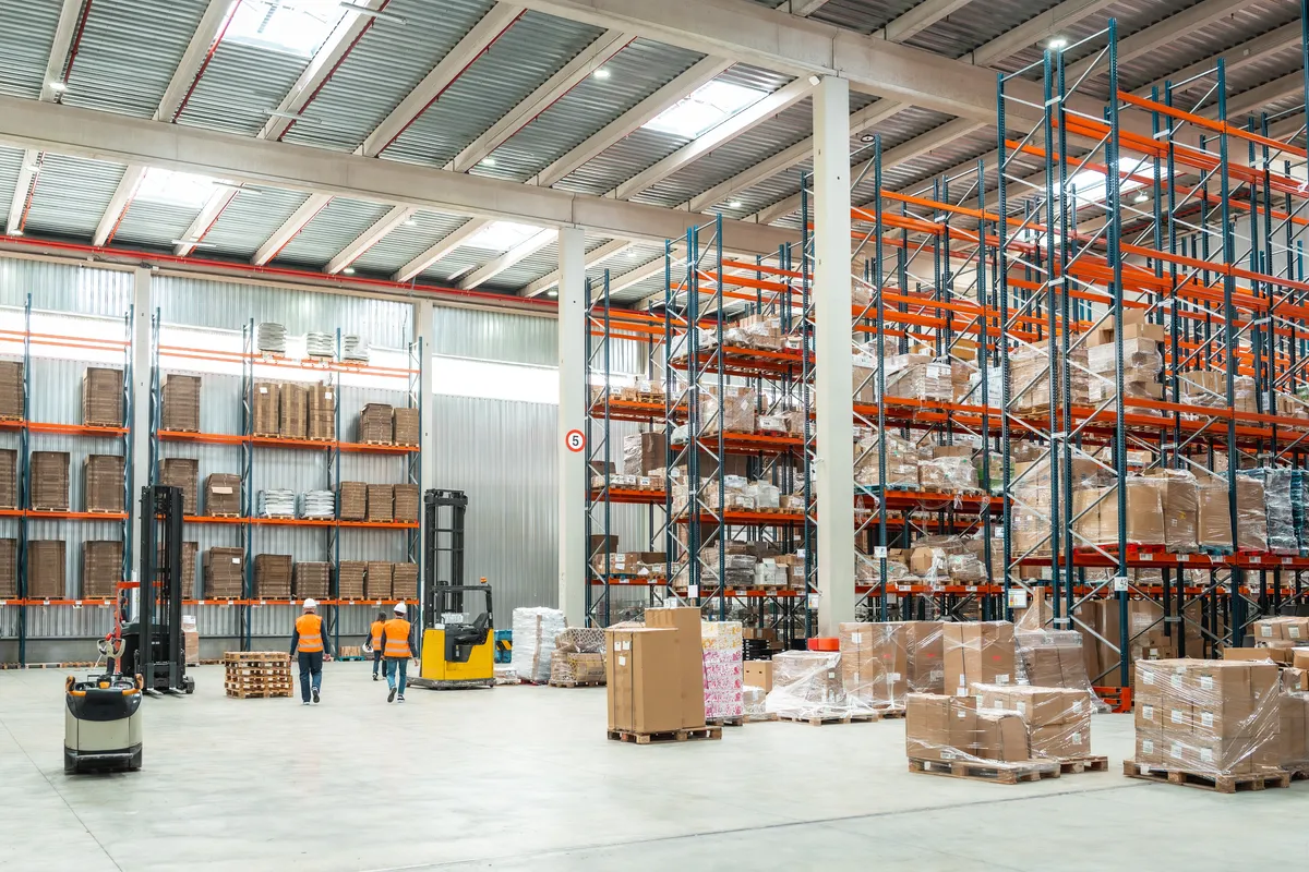 Warehouse workers managing logistics with a forklift among tall pallet racking