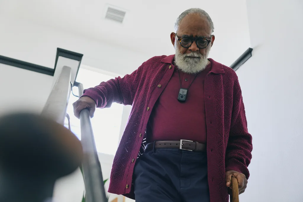 A senior man carefully descending a staircase at home while wearing a Security ONE medical alert pendant with fall detection