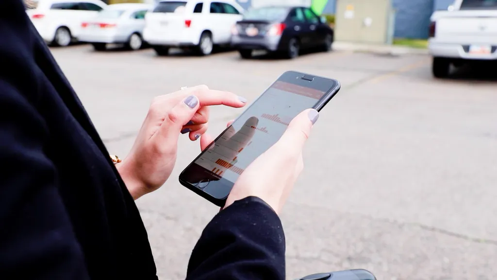 A person checking their business security on the Alarm.com app on their phone while standing in a parking lot