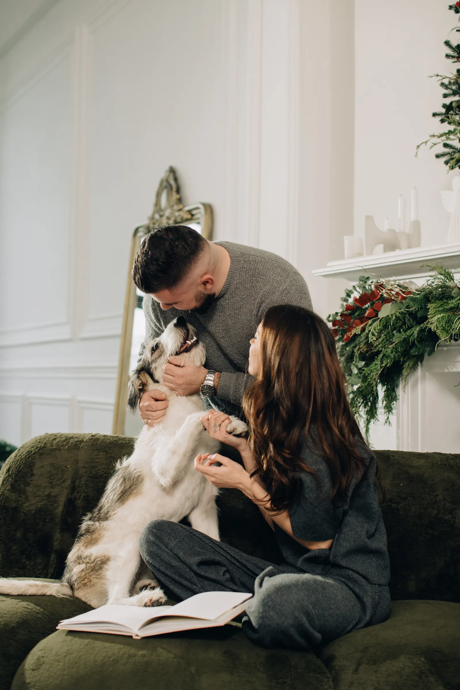 A couple cuddling their dog on a green couch in a comfortable, secure home